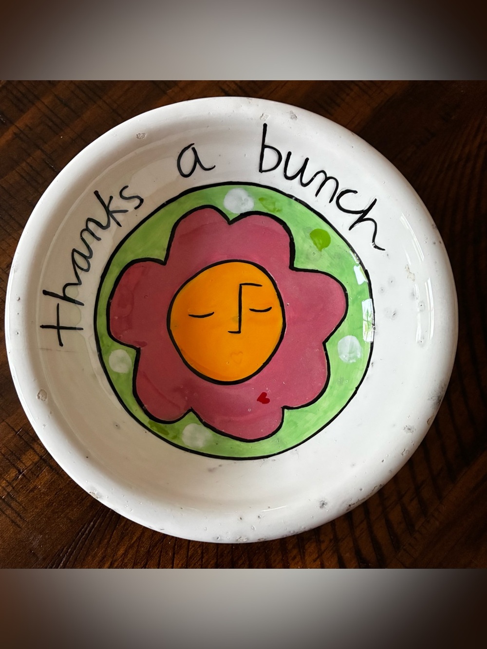 Hand-painted ceramic bowl by Sandra Magsamen with a flower and text.